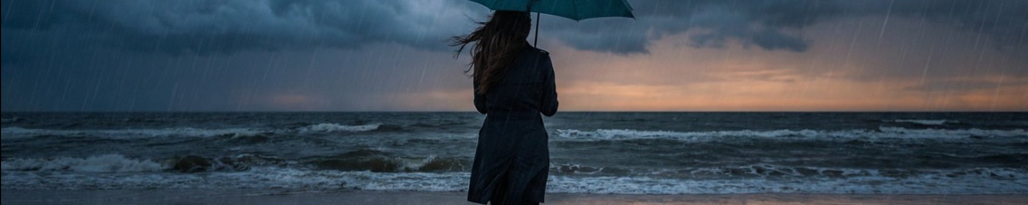 Woman standing in the rain on a stormy beach