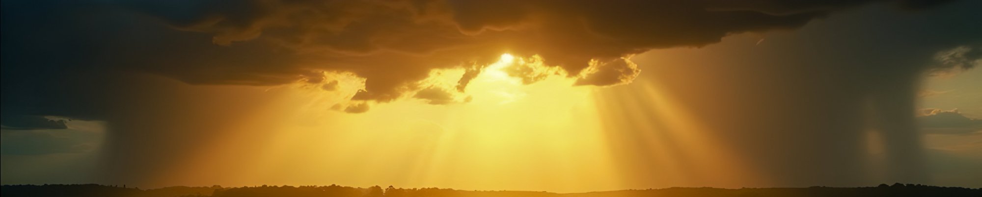 Storm clouds parting to reveal golden light over a meadow